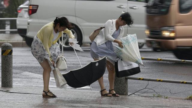 Les Japonais bravaient les puissantes rafales de vent et les fortes pluies lundi matin. [EPA/Keystone - Kimimasa Mayama]