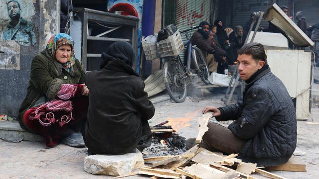 Des habitants d'un quartier Alep est se réchauffent autour d'un chauffage de fortune en attente de leur évacuation. [Abdalrhman Ismail]