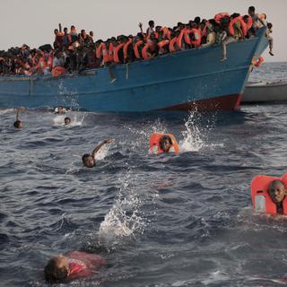 Des migrants sautent d'un bateau surchargé en Méditerranée lors d'une opération de sauvetage menée par une ONG le 29 août 2016. [Keystone - AP Photo/Emilio Morenatti]