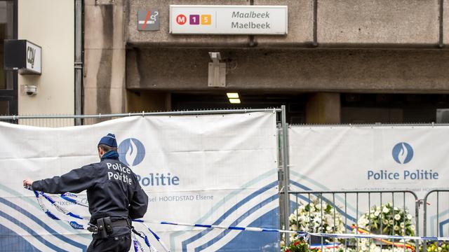 Un officier de police enlève les cordons de sécurité devant la station de métro Maelbeek, à Bruxelles, attaquée mardi. [PHILIPPE HUGUEN]