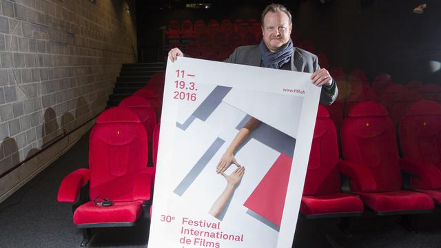 Le directeur artistique du FIFF Thierry Jobin pose avec l'affiche de la 30e édition. [Keystone - Cyril Zingaro]