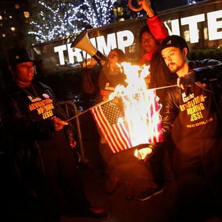 Des supporters du mouvement "NYC Revolution Club" brûlent des drapeaux américains devant le Trump International Hotel and Tower à Manhattan. [Reuters - Shannon Stapleton]