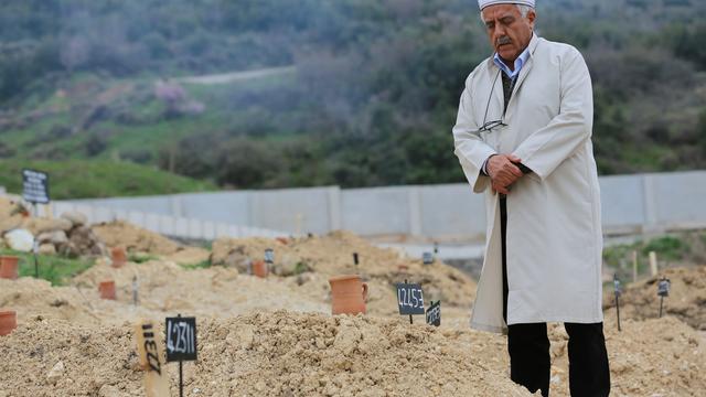 Un homme prie sur une tombe du cimetière turc d'Izmir, où de nombreux migrants non identifiés sont enterrés. [AP Photo / Keystone - Dominique Soguel]