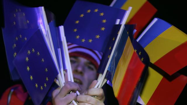 Un homme tient dans ses mains des drapeaux de l'UE et roumains. [Reuters - Bogdan Cristel]