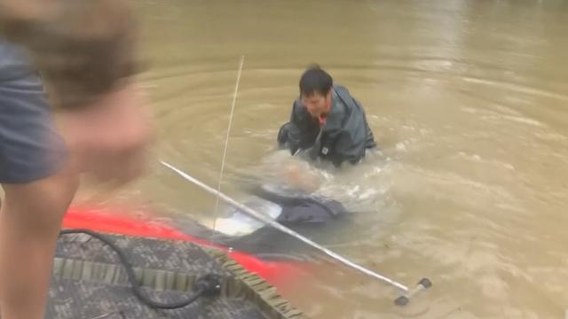 Ce secouriste est en train de découper la capote en toile d'une voiture dont la conductrice est prisonnière sous les eaux à Bâton-Rouge.