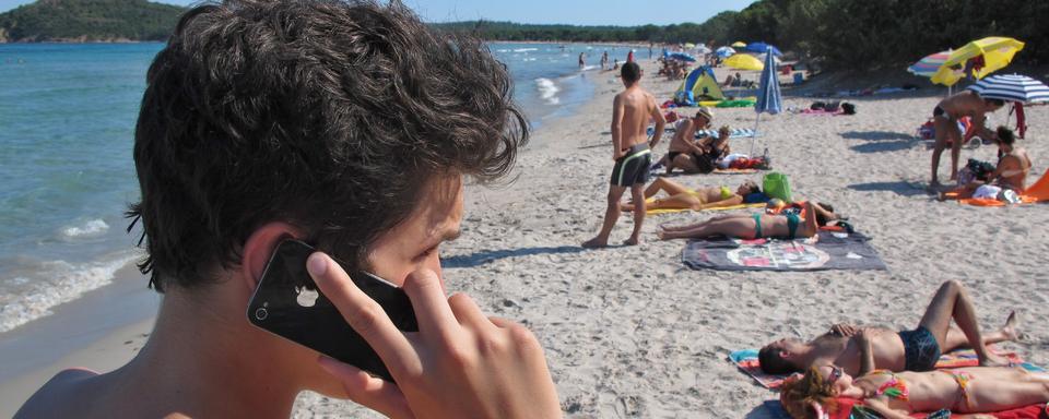 Un jeune au téléphone sur une plage en Corse. [DPA/AFP - Karl-Josef Hildebrand]