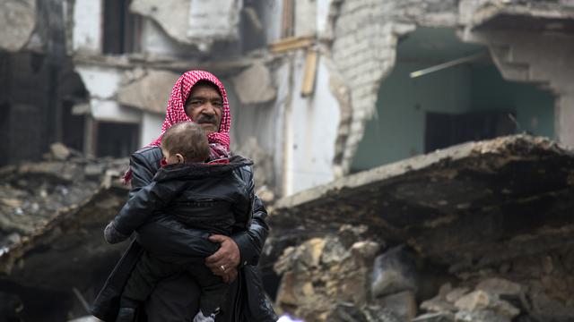 Un enfant dans les bras, un homme fuit les zones rebelles d'Alep-Est, sur le point de tomber aux mains du régime syrien. [AFP - Karam al-Masri]