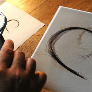 Le professeur Jean-Jacques Cassiman (Université de Louvain) examine une mèche de cheveux ayant prétendument appartenu à Napoléon Bonaparte. [AFP - Bruno Ferrandez]