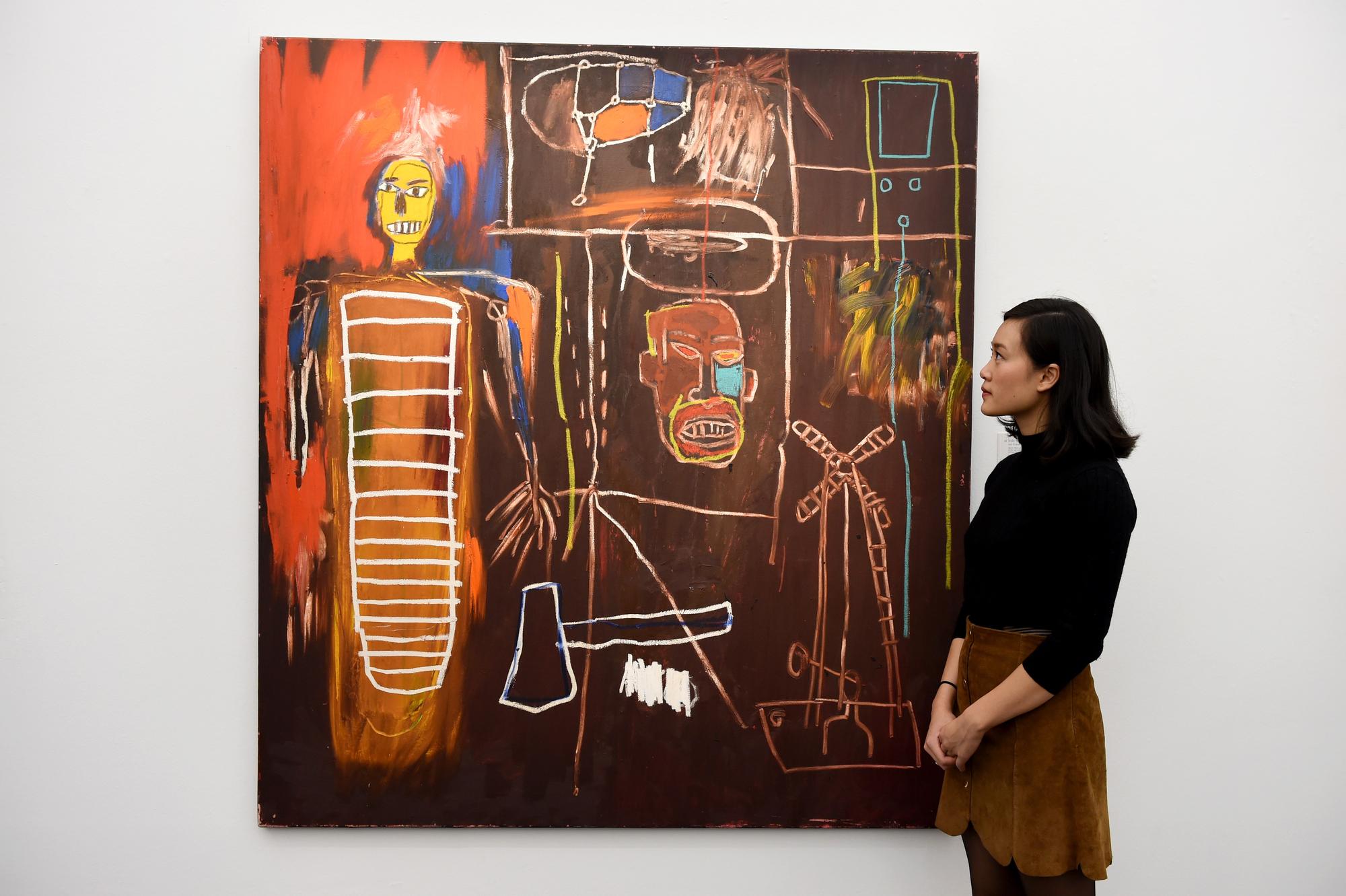 Une assistante de la galerie Sotheby's pose à côté de "Air Power", tableau de Jean-Michel Basquiat issu de la collection de David Bowie. [AFP - Kate Green / Anadolu Agency]