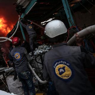 Les membres de la Défense civile syrienne, ou Casques blancs, portent secours aux victimes. [AFP - Sameer Al-Doumy]