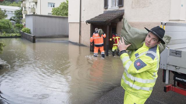 Des pompiers de Stansstad utilisent des sacs de sable pour empêcher l'eau d'entrer dans les habitations. [KEYSTONE - Urs Flueeler]