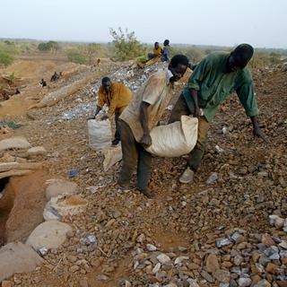 Des chercheurs d'or transportent, le 23 avril 2002 près du village de Bagassi au Burkina Faso, un sac de pierres extraits d'une mine. [AFP - Georges Gobet]