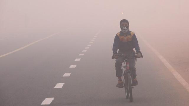 Un enfant muni d'un masque anti-pollution roule à vélo à New Delhi, plongée dans un brouillard toxique, ce lundi 31 octobre 2016. [EPA/RAJAT GUPTA]