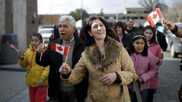 Des réfugiés syriens munis de drapeaux canadiens à Toronto en décembre 2015. [Reuters - Mark Binch]