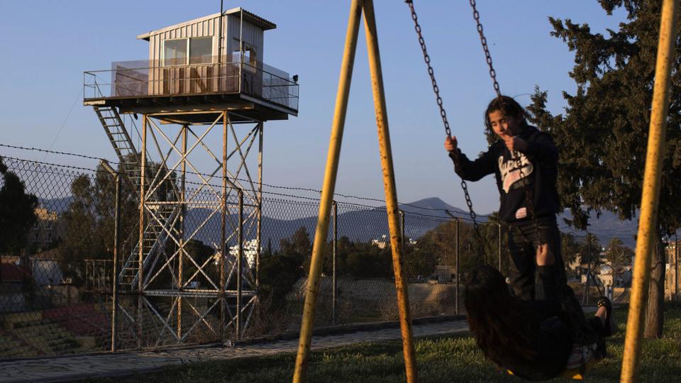 Des enfants chypriotes turcs jouent au pied de la barrière de séparation à Nicosie. [Reuters - Neil Hall]