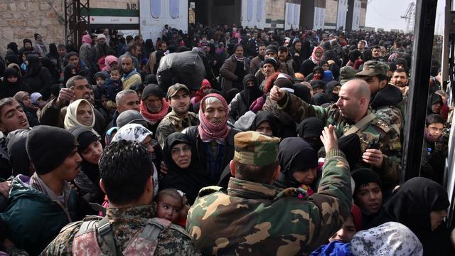 Des familles syriennes cherchent à monter dans un bus du gouvernement afin de quitter Alep assiégée. [George OURFALIAN - AFP]