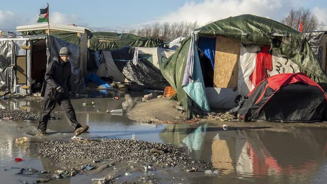 Un migrant passe devant des tentes de la "jungle" de Calais. [EPA/Keystone - Julien Warnand]