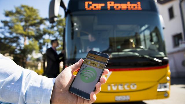 Une personne montre le fonctionnement du système de billets électroniques CIBO (Check-in, Be-out) testé par CarPostal. [Jean-Christophe Bott]