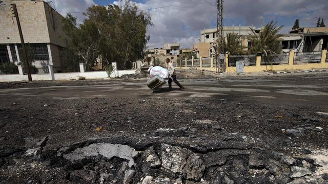 Un Syrien pousse un chariot d'affaires dans le centre du pays. [Hassan Ammar]