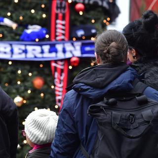 Des passants rendent hommage aux victimes de Berlin sur les lieux de l'attentat la veille de Noël. [AFP - JOHN MACDOUGALL]