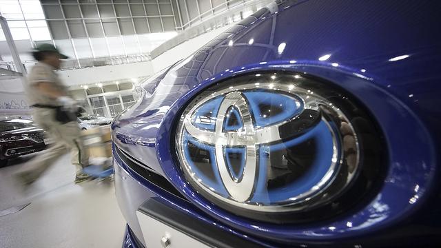 Un ouvrier passe derrière une voiture Toyota à Tokyo. [Keystone - Eugene Hoshiko]