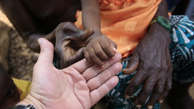 Un enfant africain tient la main d'un adulte européen (image d'illustration).