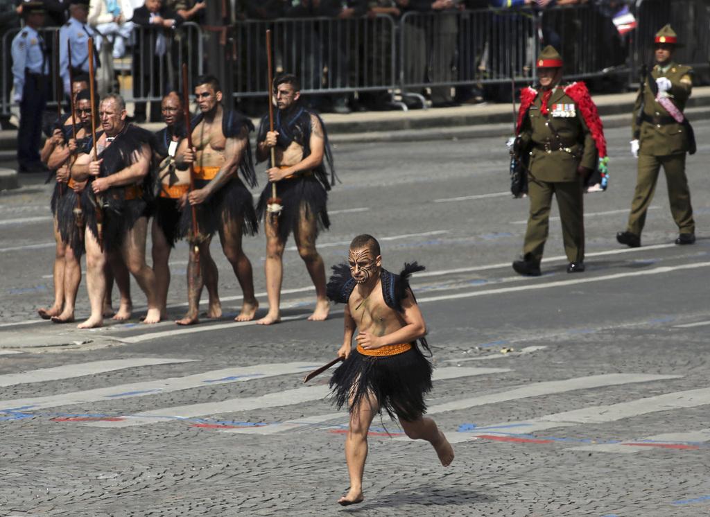Six guerriers maoris de Nouvelle-Zélande en tenue traditionnelle lors du défilé. [Keystone - AP Photo/Thibault Camus]