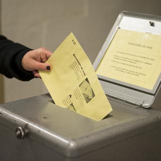 Une personne glisse son bulletin de vote à Yverdon. [Jean-Christophe Bott]