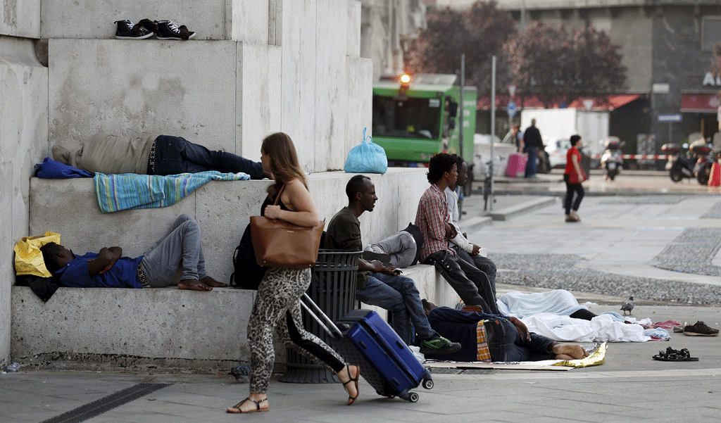 Des migrants près de la gare de Milan. [Reuters - Stefano Rellandini]
