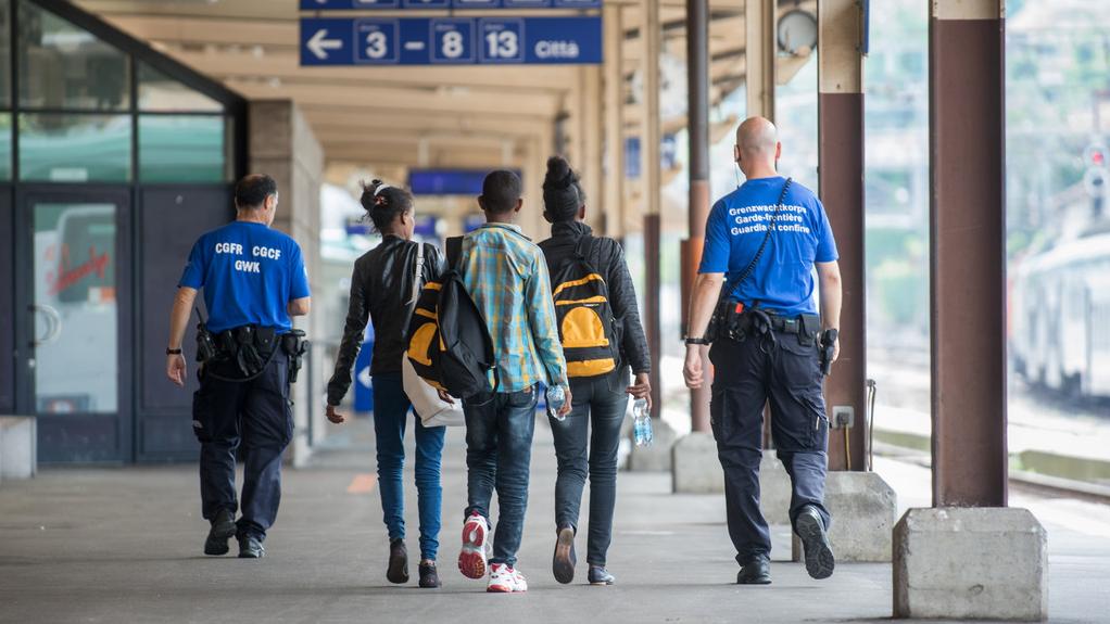 Un groupe de migrants escorté par des gardes-frontière à la gare de Chiasso. [KEYSTONE - Ti-Press/Francesca Agosta]