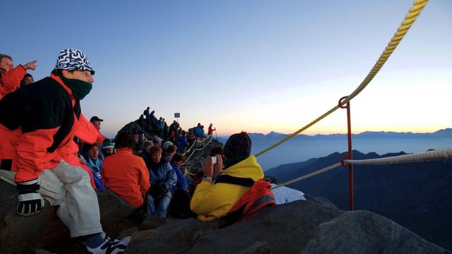 Des touristes admirent le coucher du soleil depuis le Mont Fort (VS).