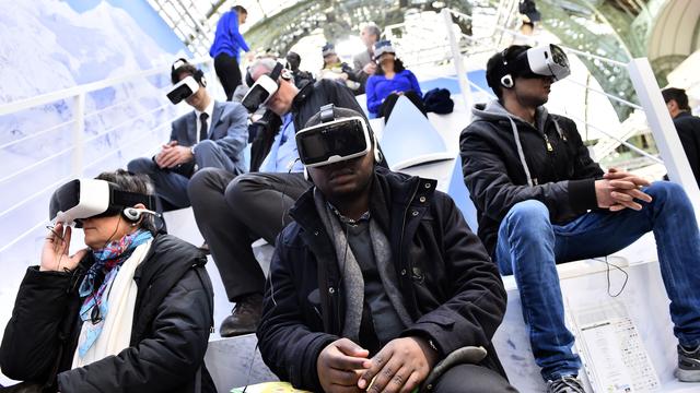 Des visiteurs de la COP21 testent des casques de réalité virtuelle. [AFP - Loïc Venance]