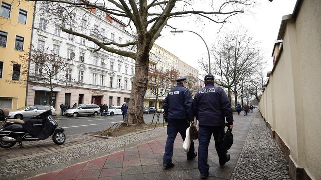 Deux policiers passent devant le bâtiment dans lequel se trouve la mosquée à laquelle se serait rendu l'auteur présumé de l'attentat de Berlin. [AFP - TOBIAS SCHWARZ]