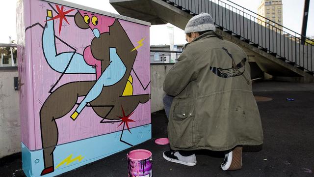 Un grapheur pose devant une armoire électrique dans les rues de Lausanne. [Keystone - Jean-Christophe Bott]