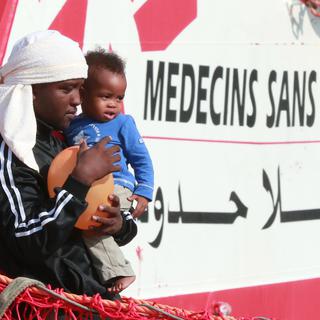 Un migrant et un enfant descendent du bateau Vox Prudence de l'ONG Médecins sans frontières le 14 juillet 2017. [AFP - CARLO HERMANN]