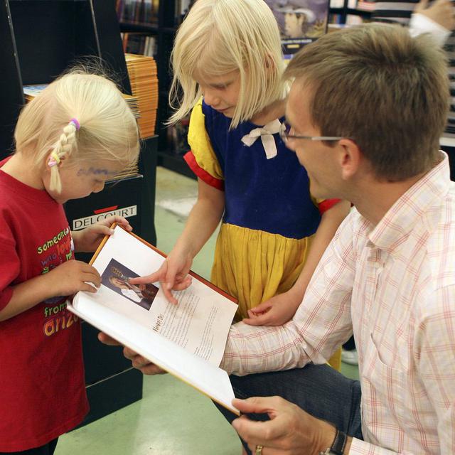 Un père et ses deux filles lisent une BD lors de la 3e edition de BD-FIL en 2007. [Keystone - Dominic Favre]