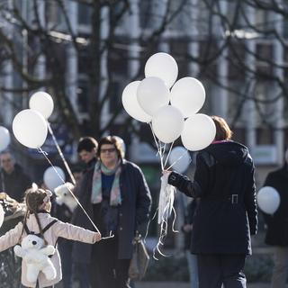 Une femme et une fille distribuent des ballons blancs lors d'une Marche Blanche, samedi 18 février 2017 à Fribourg [Keystone - ALESSANDRO DELLA VALLE]