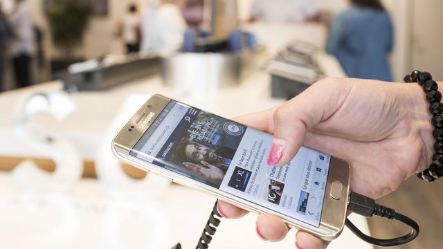 Un client teste un téléphone mobile dans un Swisscom shop à Lausanne. [Keystone - Christian Beutler)]