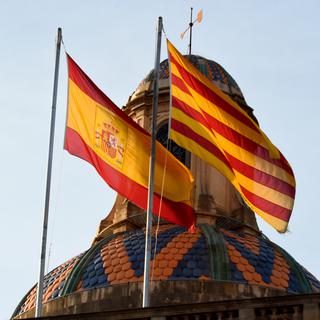 Les drapeaux espagnol et catalan en arrière-fond du palais de la Generalitat, à Barcelone (image prétexte). [AFP - Andrej Sokolow / DPA]