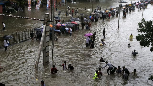 Des habitants tentent de traverser une rue transformée en rivière, ce mardi 29 août 2017 à Bombay. [AP Photo/Rajanish Kakade]