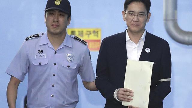 L'héritier de Samsung Lee Jae-yong, menotté, quitte le tribunal après le verdict le condamnant à 5 ans de prison. [Keystone - Chung Sung-Jun]