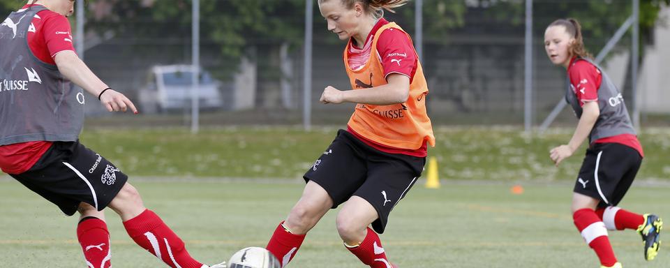 Encourager les filles à jouer au football peut faire partie des stratégies d'éducation pour lutter contre les inégalités liées au genre. [Keystone - Peter Klaunzer]