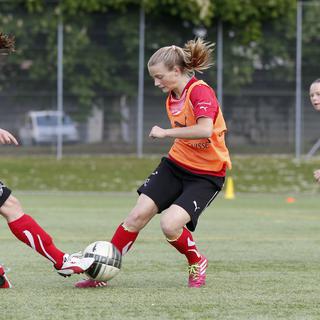 Encourager les filles à jouer au football peut faire partie des stratégies d'éducation pour lutter contre les inégalités liées au genre. [Keystone - Peter Klaunzer]