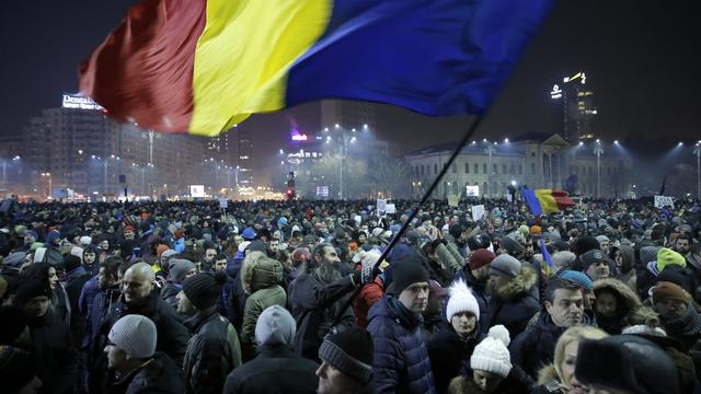 Un drapeau roumain flotte au-dessus de la manifestation de mardi soir à Bucarest. [KEYSTONE - ROBERT GHEMENT]