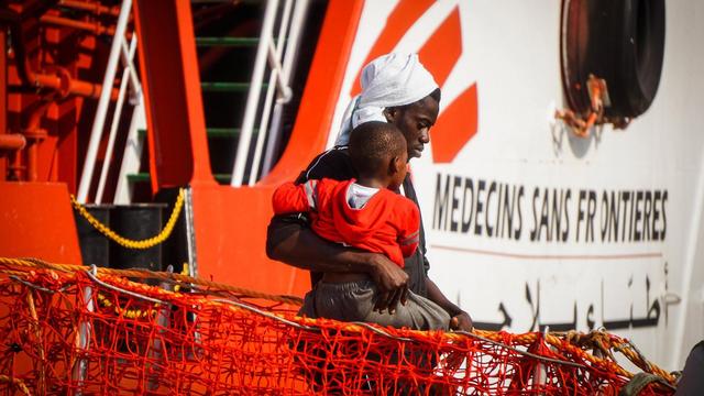 Un homme et un jeune garçon débarquent d'un navire de Médecins sans frontière dans le port de Salerne, dans le sud de l'Italie. [Keystone - Cesare Abbate]