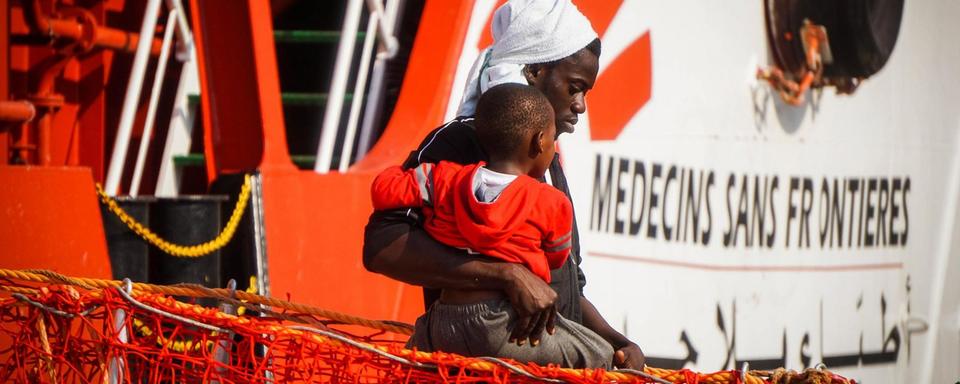 Un homme et un jeune garçon débarquent d'un navire de Médecins sans frontière dans le port de Salerne, dans le sud de l'Italie. [Keystone - Cesare Abbate]