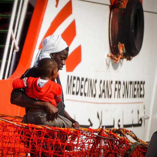 Un homme et un jeune garçon débarquent d'un navire de Médecins sans frontière dans le port de Salerne, dans le sud de l'Italie. [Keystone - Cesare Abbate]