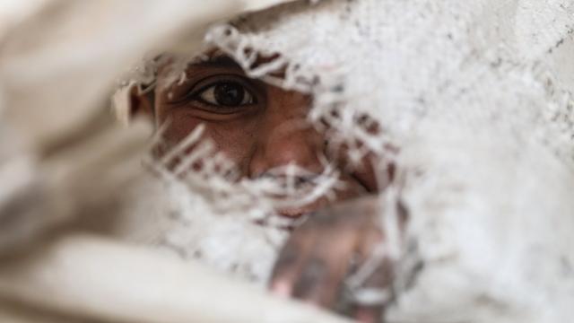 Les habitants de la Ghouta orientale en Syrie, comme cet enfant, vivent dans une ville en partie détruite. Depuis aujourd'hui, des personnes en détresse médicale sont évacuées de la région [Keystone - MOHAMMED BADRA]