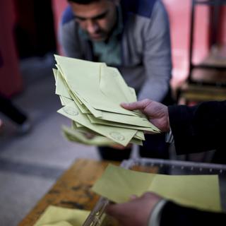 Membres d'un comité électoral recueillant dimanche des bulletins de vote dans un bureau de Diyarbakir, dans le sud-ouest de la Turquie. [AP/Keystone - Emre Tazegul]