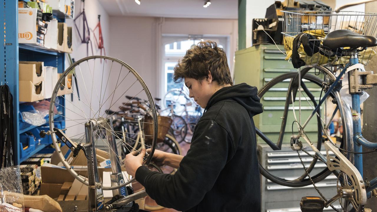 Un apprenti en mécanique vélo dans son atelier à Zurich. [Keystone - Christian Beutler]